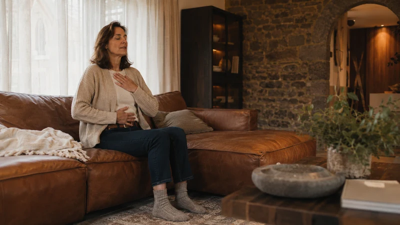 Femme assise, une main sur la poitrine et une main sur le ventre, illustrant un point d’ancrage physique